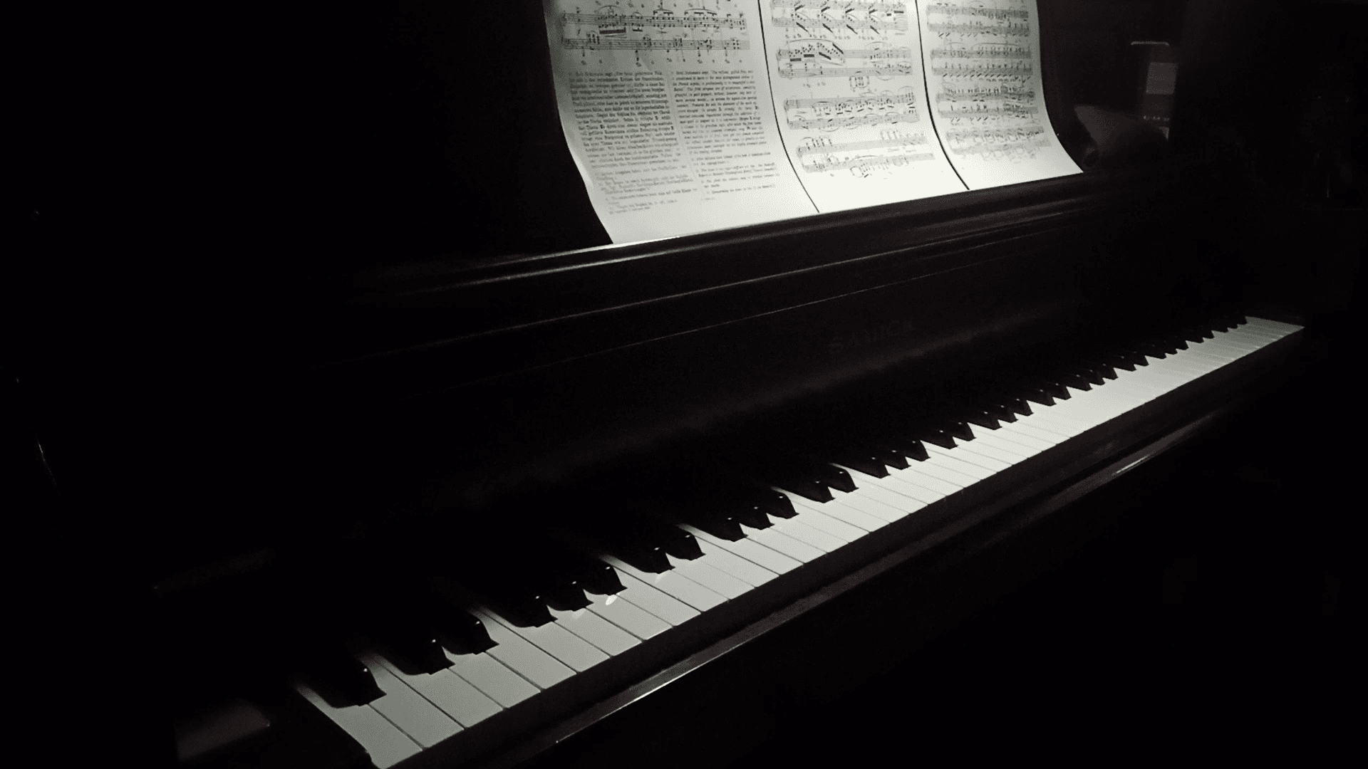 Upright piano keyboard lit by a single lamp